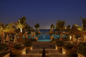 Sofitel Dubai The Palm, a lit resort pool and gardens at dusk